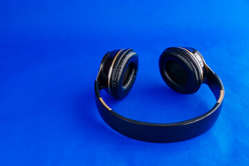black headphones on a white plate and electric blue background ready for consumption