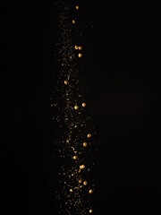 Fototapeta na wymiar A stream of golden colored spices in a frozen flight isolated on a black background. Abstraction. Minimalism. Spices and seasonings, cooking, supermarket, advertising, banner.