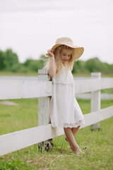 Beautiful little blonde girl on a ranch on a summer day.
