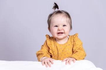 Fotobehang süß lachendes Baby mit lustigem Haarzopf in gelbem Kleid  © Ingeborg Zeh