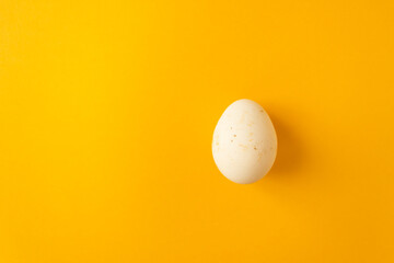 Single natural farm chicken egg isolated on yellow background. Easter holiday concept.