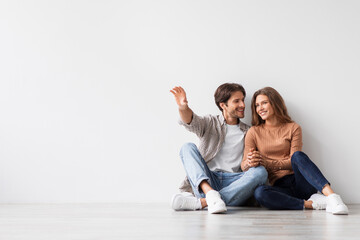 Satisfied millennial caucasian guy and lady planning future interior, dream, sit on floor