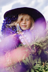 Portrait of a pretty girl in hat with bouquets of lupins in the face