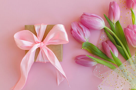 Happy womens day. 8 march. Pink tulips bouquet and gift box on pink background flat lay. Happy Mothers day. Greeting card. Gentle image