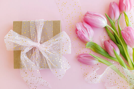 Pink tulips bouquet and gift box on pink background flat lay. Happy womens day. 8 march. Happy Mothers day. Greeting card. Gentle image