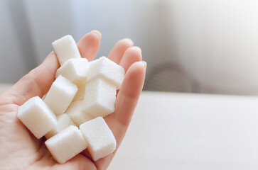 close up of White sugar cubes in the hand. The concept of unhealthy eating.