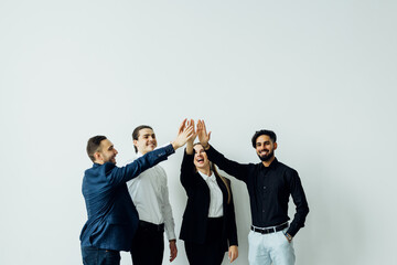 Multinational colleagues diverse business people standing in modern office giving high five holding hands together celebrating great results in common business. Togetherness and success concept