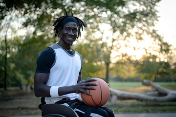 African man with a disability playing basketball on a wheelchair, portrait of smiling adult male...