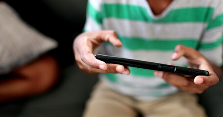 Child hands using cellphone close-up. African black ethnicity kid hand playing video-game with phone