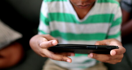 Child hands using cellphone close-up. African black ethnicity kid hand playing video-game with phone