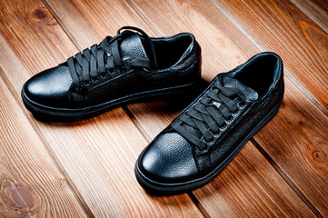 Black imitation leather shoes laced with wide laces. Close-up shot.