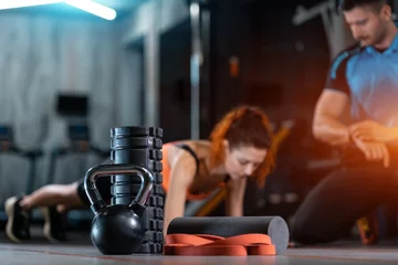 Tuinposter fitness female exercising plank with personal trainer with equipment in gym © goami