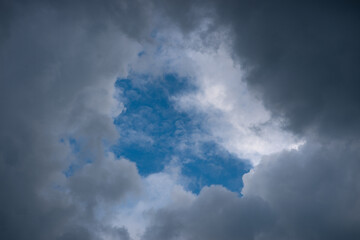 Overhanging dark leaden and heavy clouds surround the blue sunset sky