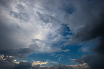Overhanging dark lead and heavy clouds along with white and orange clouds surround the blue sunset sky
