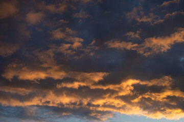 Dense painted clouds at sunset against a blue sky