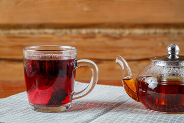 Cup and teapot of hibiscus tea on the table on a napkin