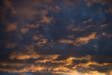 Naklejka na ściany i meble Dense dramatic painted clouds at sunset of the day against a blue sky
