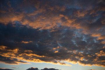 Dense dramatic painted clouds at sunset of the day against a blue sky