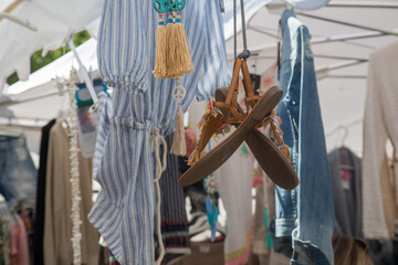 Beautiful leather sandals with colorful fringes hanging from a tent roof - shoes for women and for summer and beach, sold at a farmers market in Provence, Côte d ´azur, France, blurred background