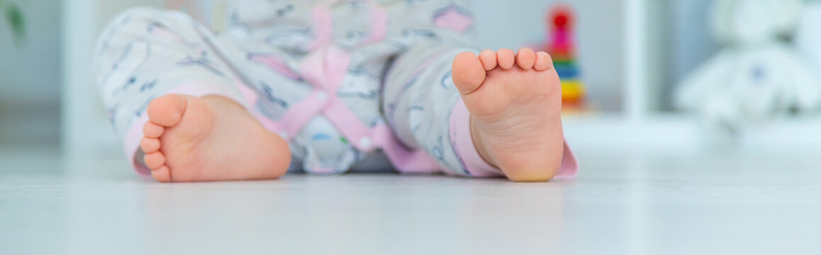 The baby's feet are sitting on the floor. Selective focus.