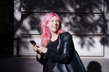 Obraz premium happy girl in rocker look with cell phone in hand outdoors