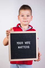 kid boy holding letter board with text Your Vote Matters on white background