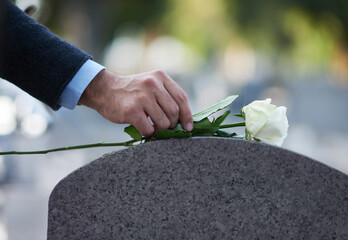 Paying his respects. Cropped shot of a man placing a white rose on a grave.