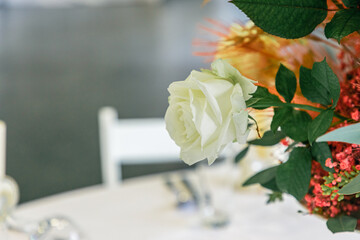 Big floral wedding centrepiece, made out of white roses and pampas grass on a white table in a reception venue.