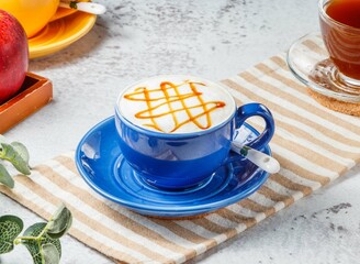 Hot caramel macchiato in blue cup on mat with grey background breakfast drink