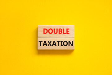 Double taxation symbol. Concept words Double taxation on wooden blocks on a beautiful yellow table yellow background. Business tax and double taxation concept, copy space.