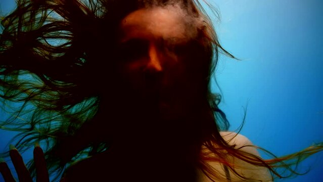 Creepy portrait of a woman underwater hair in weightlessness slow motion in the mouth white liquid flows out. A nightmare in a dream.