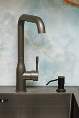Single-handle kitchen sink faucet and built-in brass liquid soap dispenser close-up