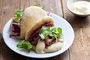 Steamed bao buns with beef steaak, pickled cucumber, erd cabbage and mustard mayo