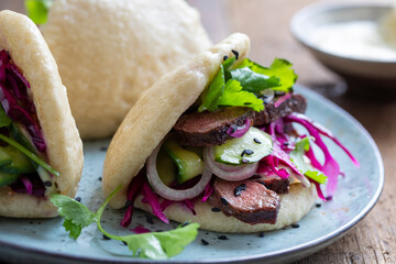 Steamed bao buns with beef steaak, pickled cucumber, erd cabbage and mustard mayo