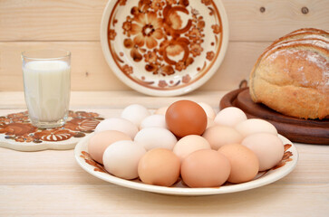 traditional farm products eggs, milk and bread on a wooden background