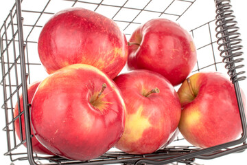 A few sweet organic, red apples with a metal wire basket, macro, isolated on a white background.

