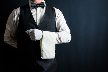 Butler or Waiter in Black Vest or Waistcoat and White Gloves Standing With Napkin Folded Over Arm....