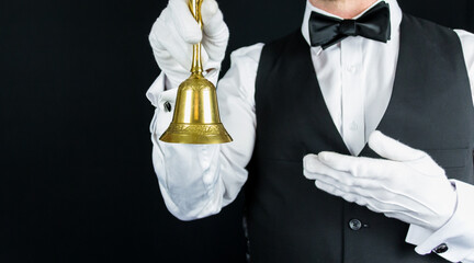 Butler or Waiter Holding Golf Bell on Black Background. Concept of Service Industry and Professional Hospitality.