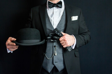 Portrait of Man in Dark Suit Holding Leather Gloves and Bowler Hat. Vintage Style and Retro Fashion...