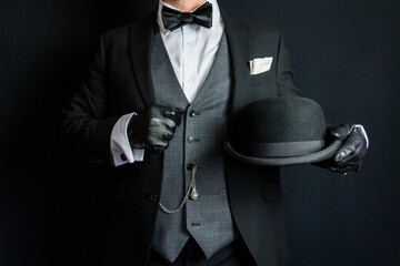 Portrait of Man in Dark Formal Suit and Leather Gloves Holding Bowler Hat. Vintage Style and Retro...