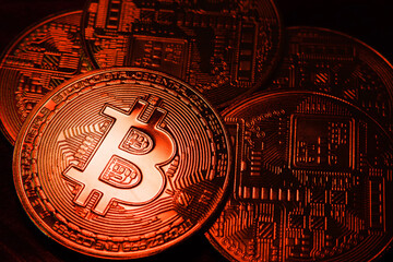 BTC coins in a beautiful red light on a dark background. Bitcoin cryptocurrency. Blockchain technology. Close-up.