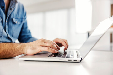 Side view of male hands typing on the laptop.