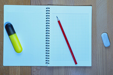 top view of school supplies - a sheet of paper and a pencil on a light wooden surface