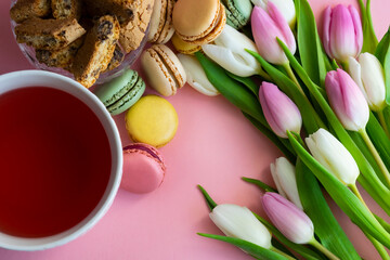 Obraz na płótnie Canvas flat lay with tulips, tea and sweets on pink background