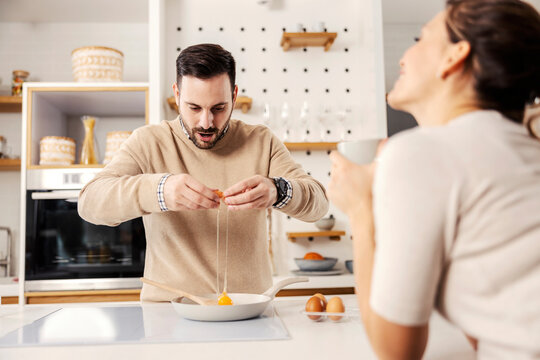 A man in the kitchen preparing sunny side up eggs for his wife at their cozy home.