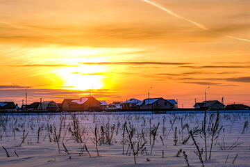 The image of a winter village in winter at sunset