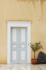 Fototapeta na wymiar Traditional Greek and mediterranean wall and doors architecture and fresh green plants in pots.