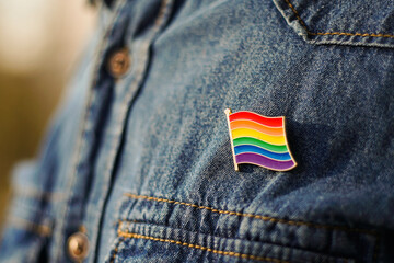 Close up of LGBT pin in the form of a flag is pinned on blue jeans jacket. LGBT rights concept. - Powered by Adobe