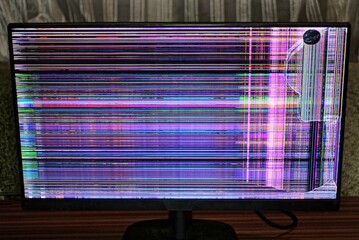 one big rectangular computer monitor with a cracked screen and colored stripes stands in the room