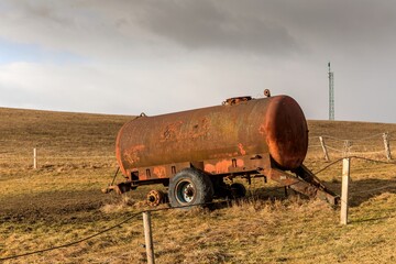 Water tank, drinker for cattle on pasture in Czech Republic. Empty pasture with rusty water tank. Cattle breeding on the farm.